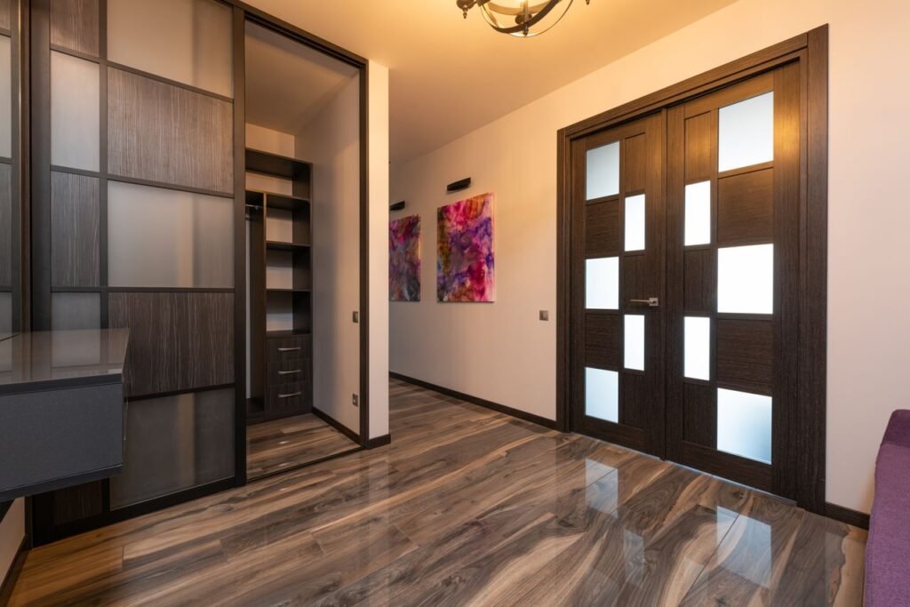 Contemporary room interior with closet on floor reflecting door against paintings on wall in light house